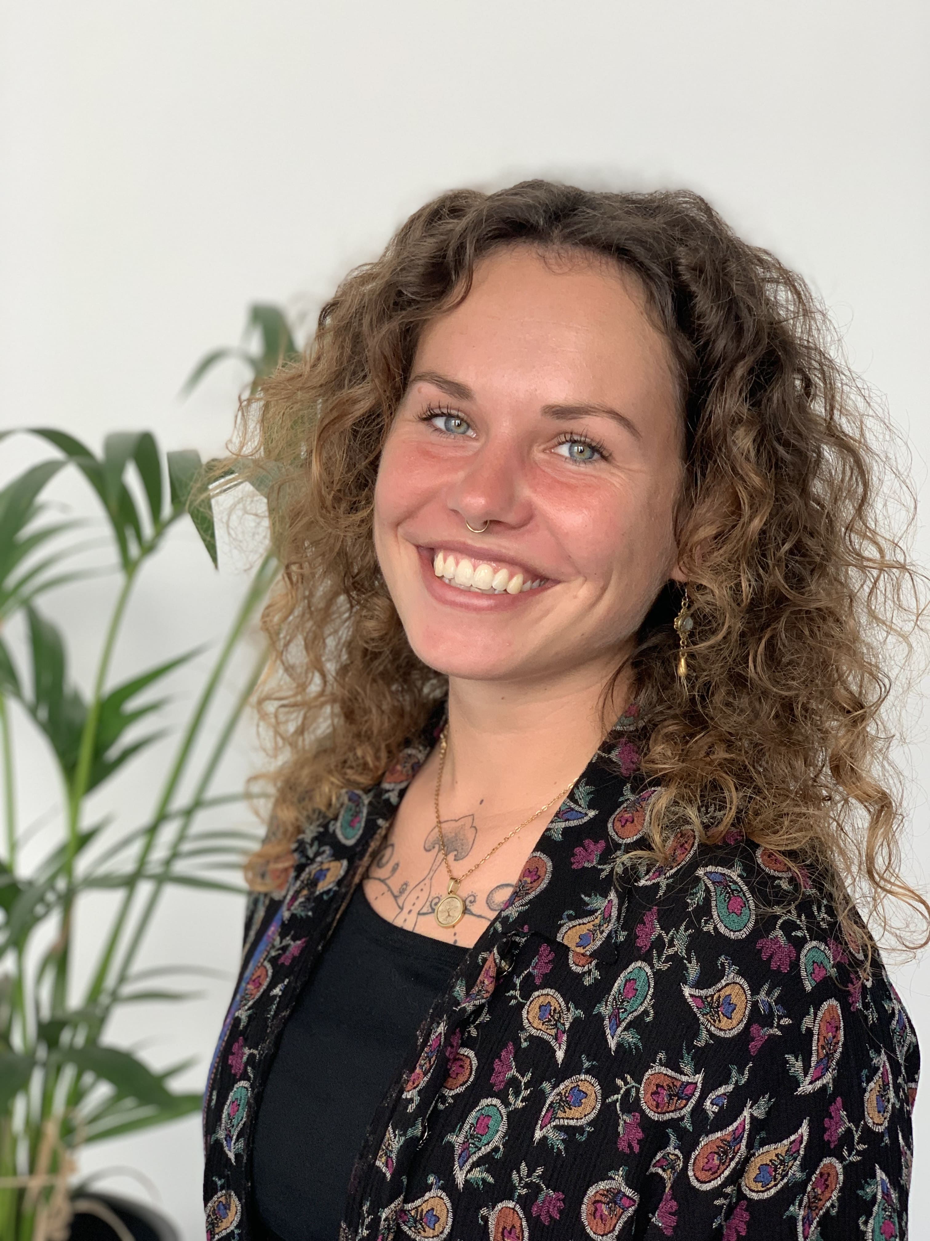 Frau mit Locken schaut in die Kamera und lacht